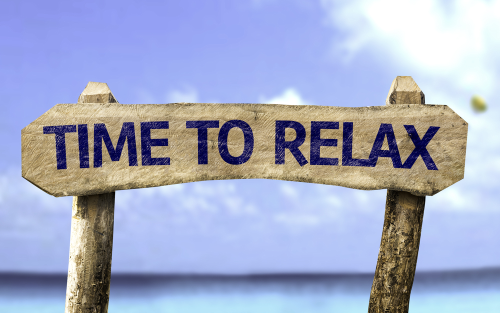 Time To Relax wooden sign with a beach on background